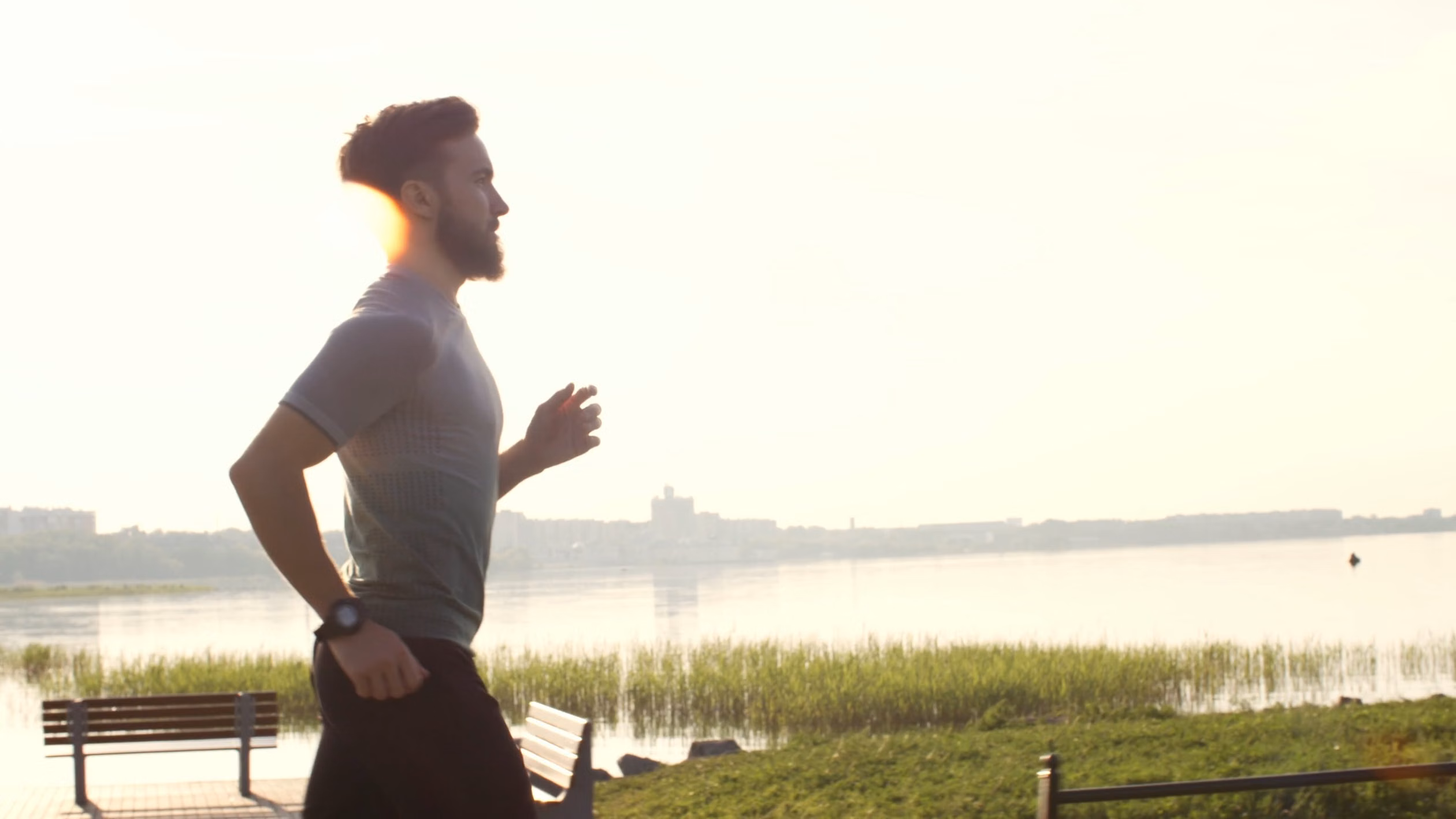 Man jogging beside a sunlit lake