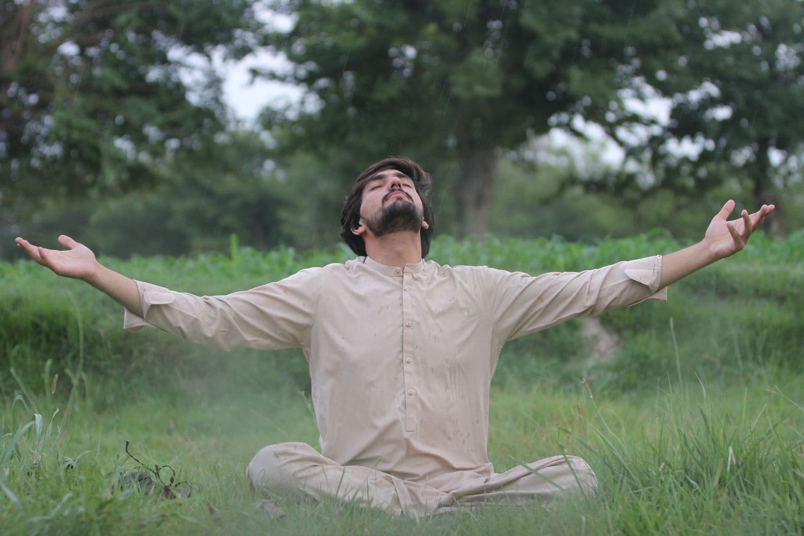 Man meditating outdoors in a green field